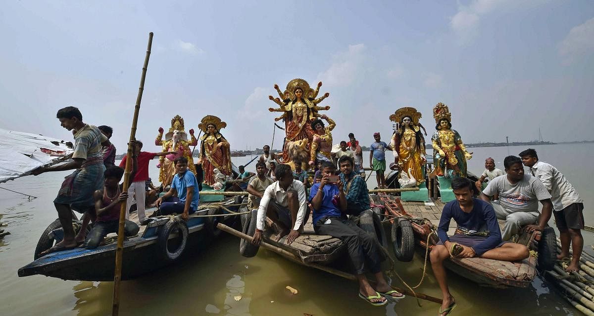 People carry idols of Goddess Durga across River Ganga to install at pandals for the upcoming Durga Puja festival, in Kolkata on Sunday. (PTI Photo)
