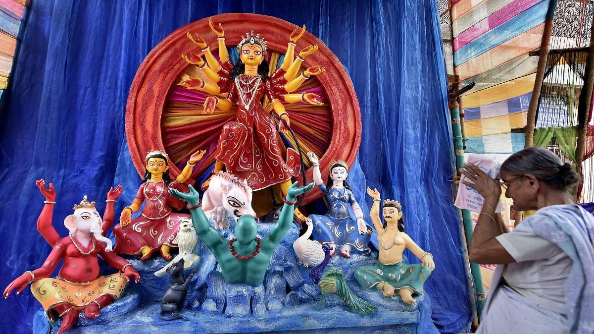 An elderly woman offers prayers in front of an idol of Goddess Durga at a puja pandal, in Kolkata. (PTI photo)