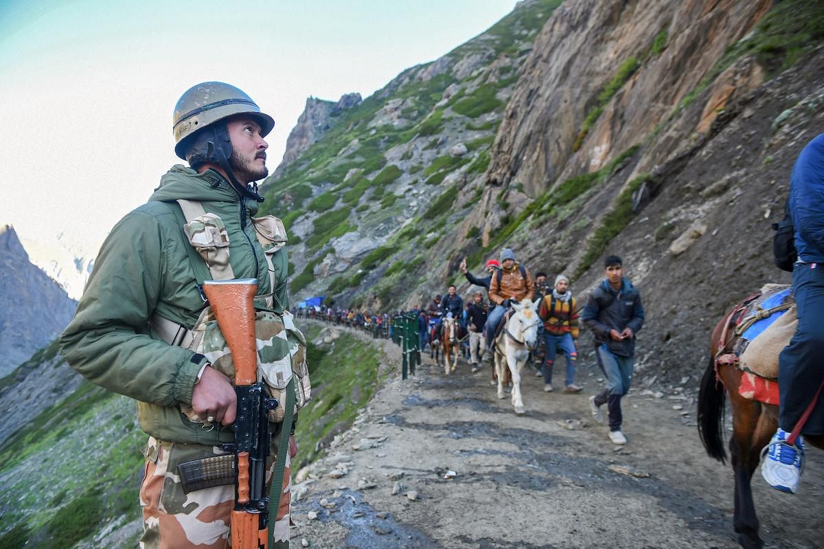 Security personnel stand guard as the first batch of pilgrims en route towards the holy cave shrine of Amarnath during the annual pilgrimage, at Baltal in central Kashmir’s Ganderbal district. (PTI Photo)