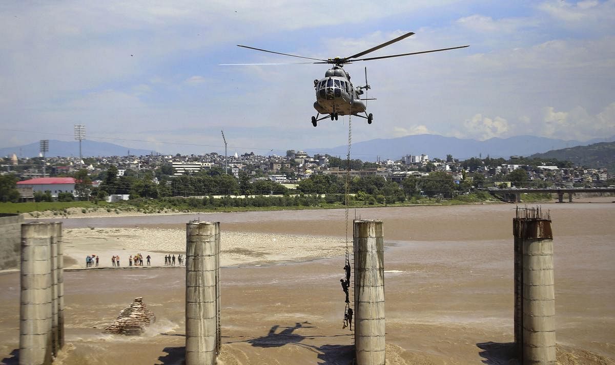 A chopper of the Indian Air Force approaches to airlift two persons stuck on an under-construction bridge on the flooded Tawi River in Jammu, Monday, Aug 19, 2019. (PTI Photo)