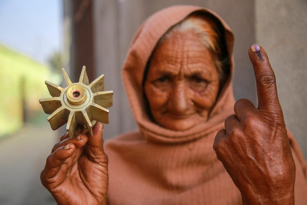 An elderly voter shows her ink-marked finger and as she holds a mortar tail fin in the other hand, after casting vote at a polling station during the 7th phase of the panchayat elections at a village, in Jammu. (PTI Photo)