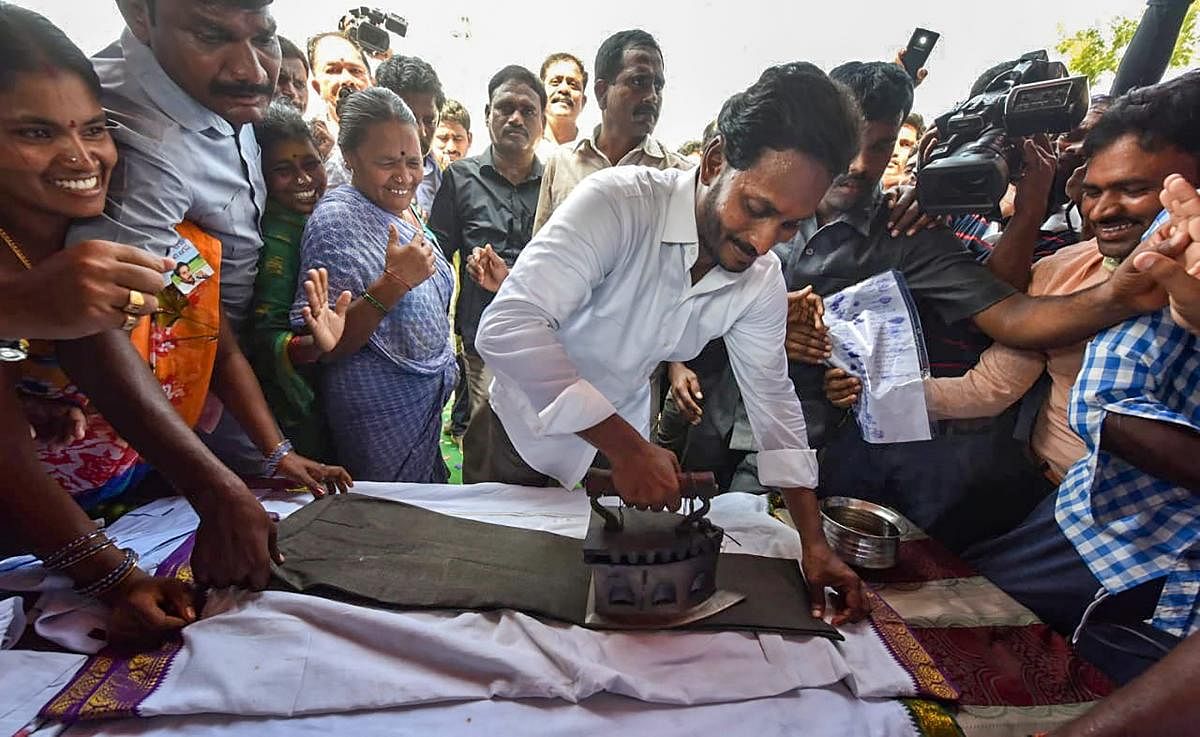 YSR Congress Party President Y S Jaganmohan Reddy irons clothes at a shop during his 'Praja Sankalpa Yatra' in Cheepurupally constituency of Vizianagaram district. (PTI photo)