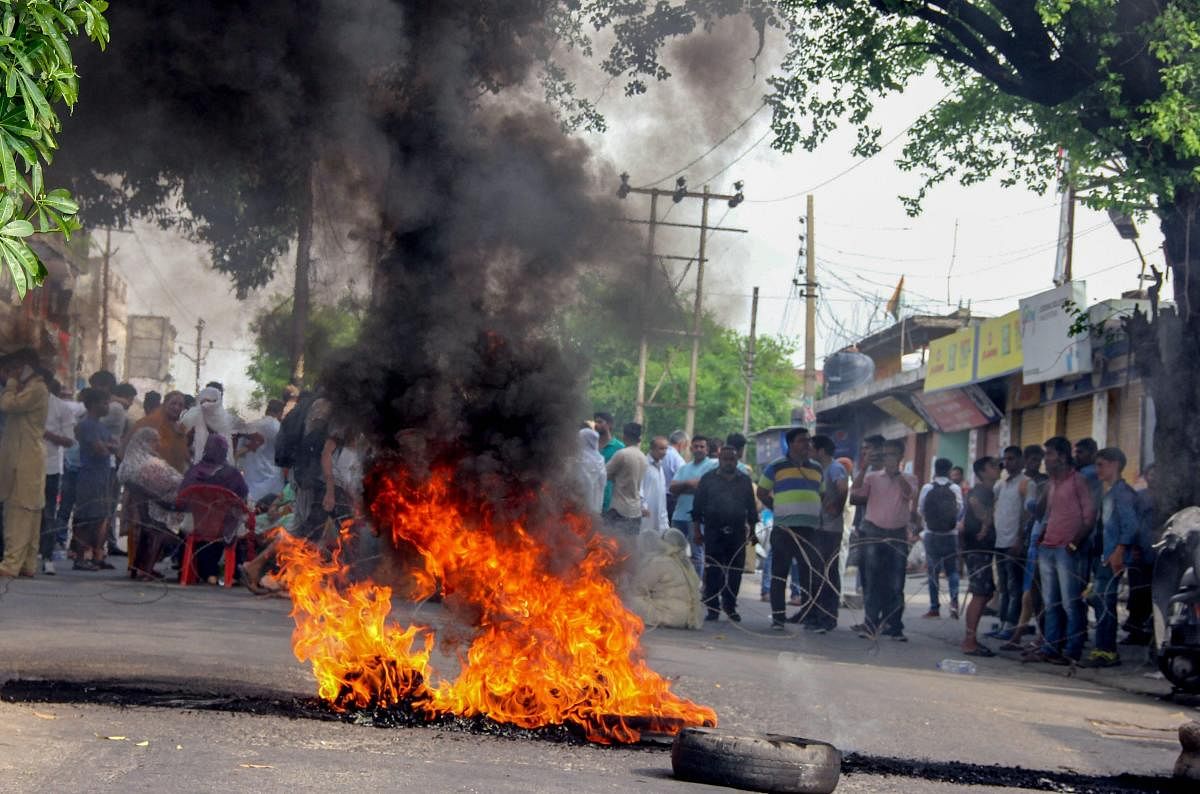People block road by burning tyres as they protest demanding inquiry into the Farooq Abdullah security breach case which lead to the death of the intruder, in Jammu. PTI photo