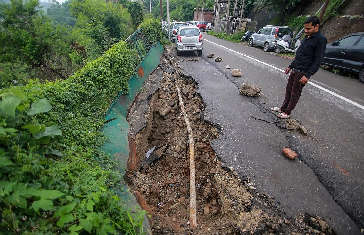 A person looks on at a caved road following monsoon rainfall, in Jammu on Monday. PTI Photo