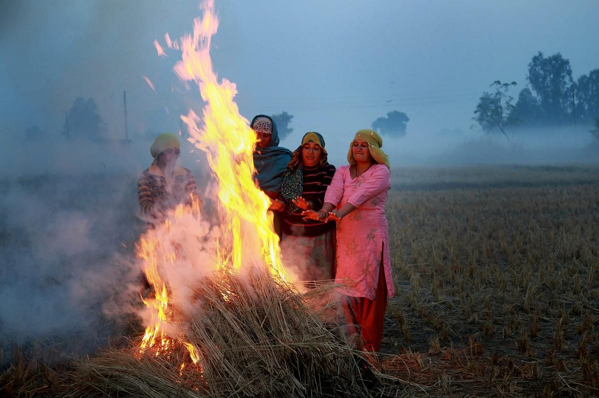 Villagers warm themselves around a bonfire at a field on the outskirts of Jammu on Tuesday. (PTI Photo)