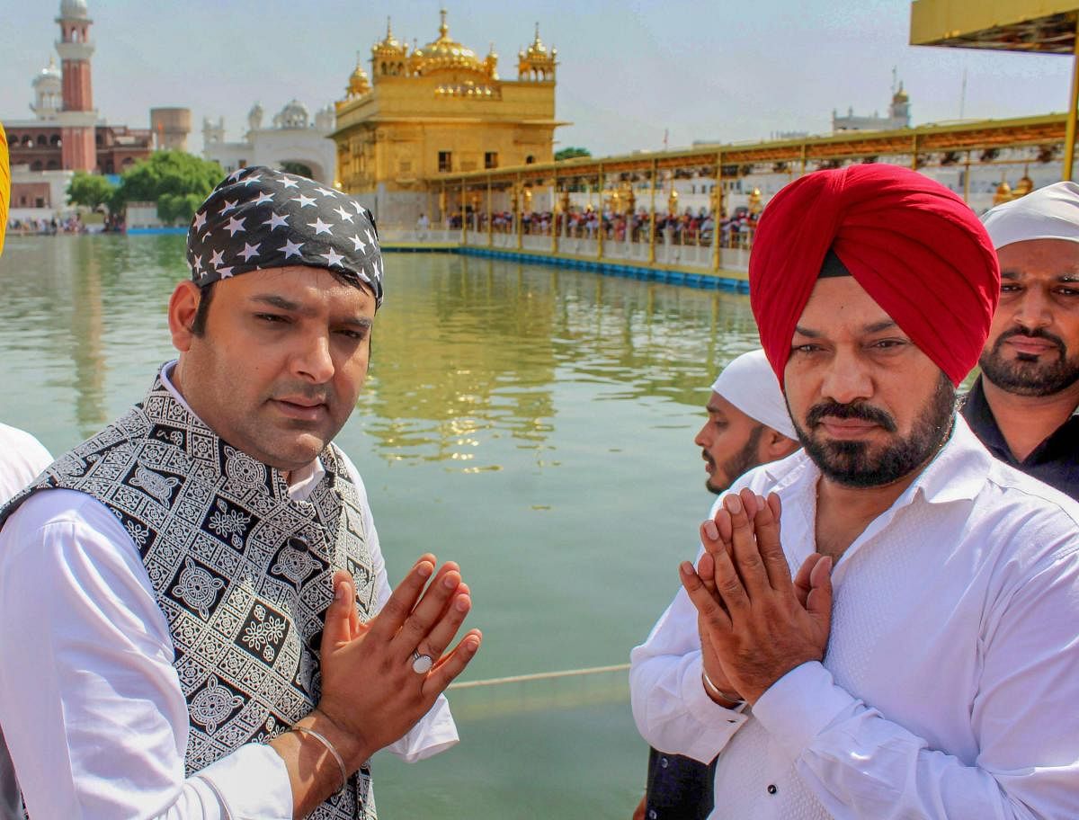 Indian comedian Kapil Sharma and Gurpreet Ghuggi offer prayers at Golden Temple during a promotion for their upcoming film
