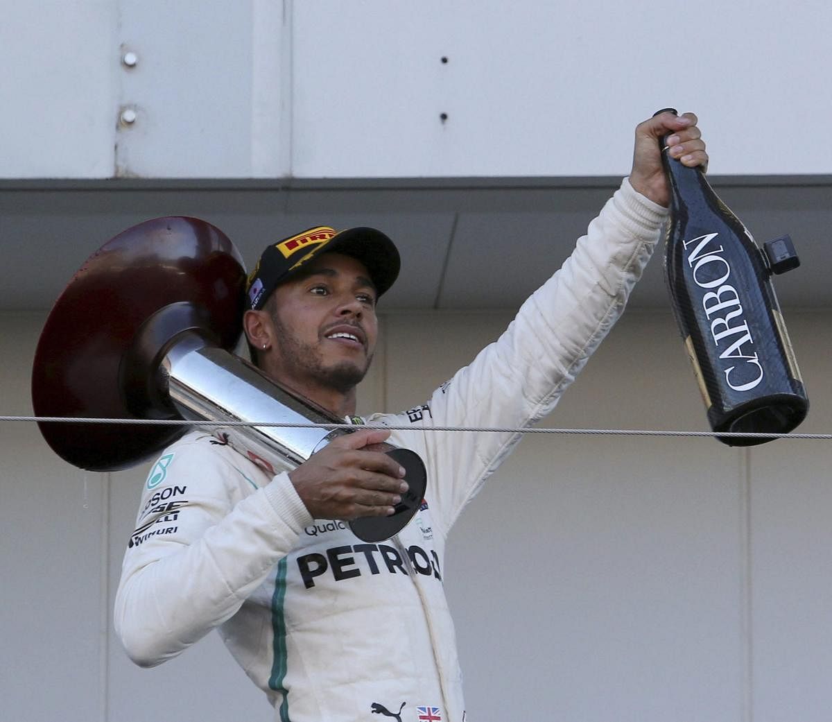 Mercedes driver Lewis Hamilton of Britain holds his trophy and a bottle of champagne on the podium after winning the Japanese Formula One Grand Prix at the Suzuka Circuit in Suzuka, central Japan on Sunday. (AP/PTI Photo)