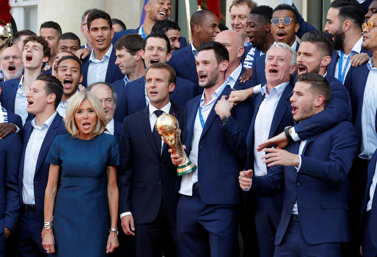 French President Emmanuel Macron and his wife Brigitte Macron pose with France soccer team captain Hugo Lloris holding the trophy, coach Didier Deschamps and players before a reception to honour the France soccer team after their victory in the 2018 Russia Soccer World Cup, at the Elysee Palace in Paris, France, July 16, 2018. (REUTERS/Philippe Wojazer)