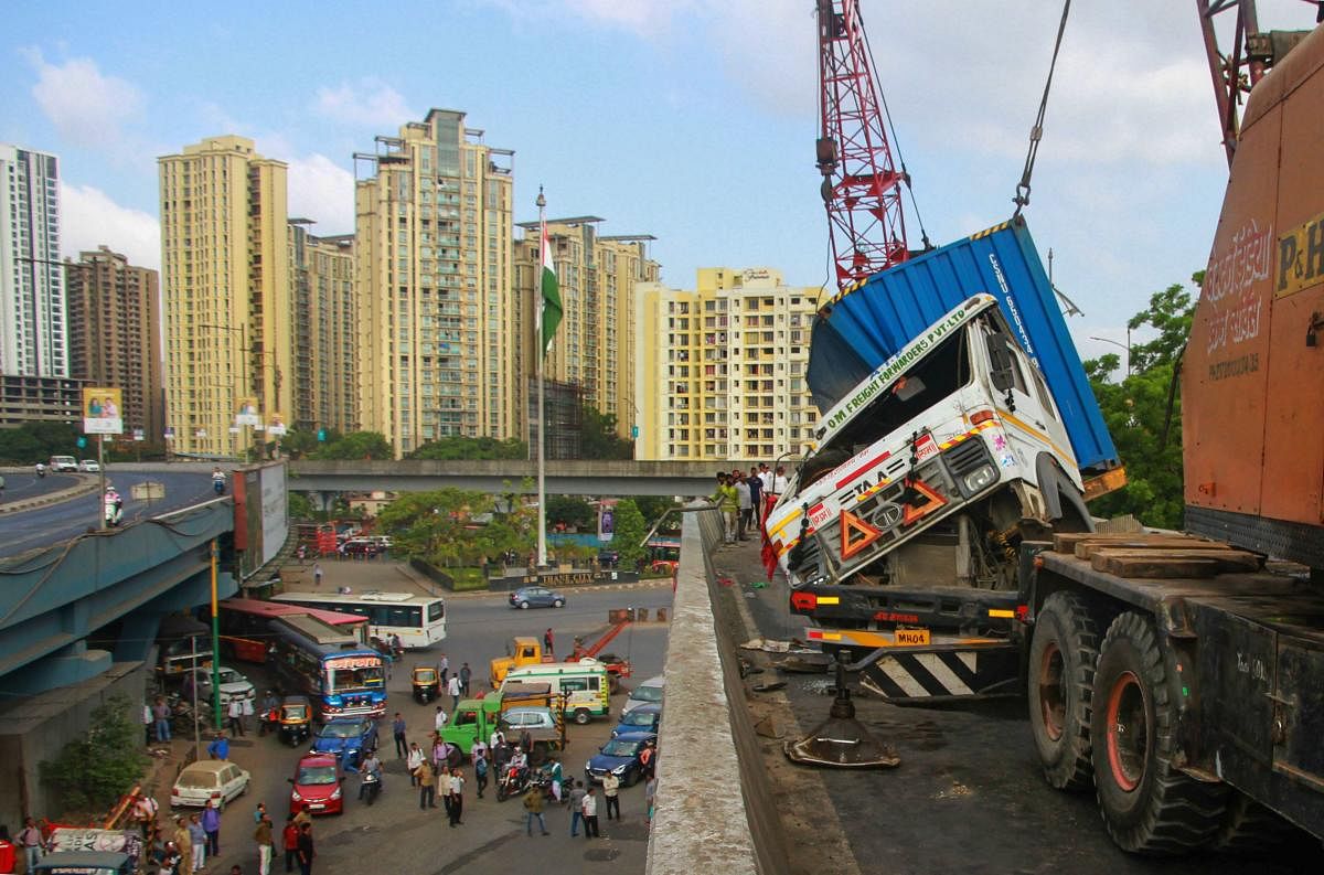 A container is lifted by a crane after it had toppled on a sharp turn at Majiwada flyover, in Thane. PTI Photo