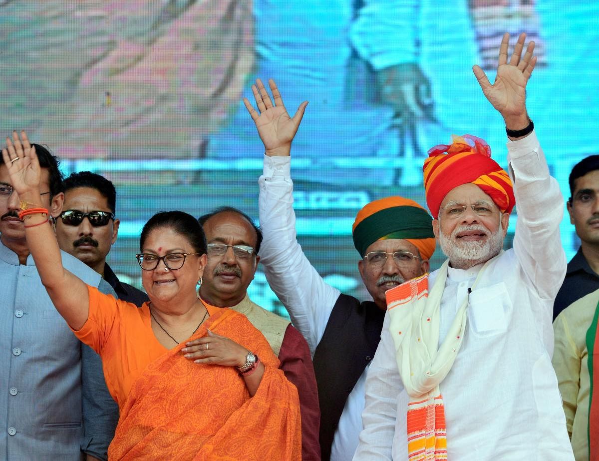 Prime Minister Narendra Modi and Rajasthan Chief Minister Vasundhara Raje greet their supporters during 'Vijay Sankalp Sabha' in Ajmer on Saturday. (PTI Photo)