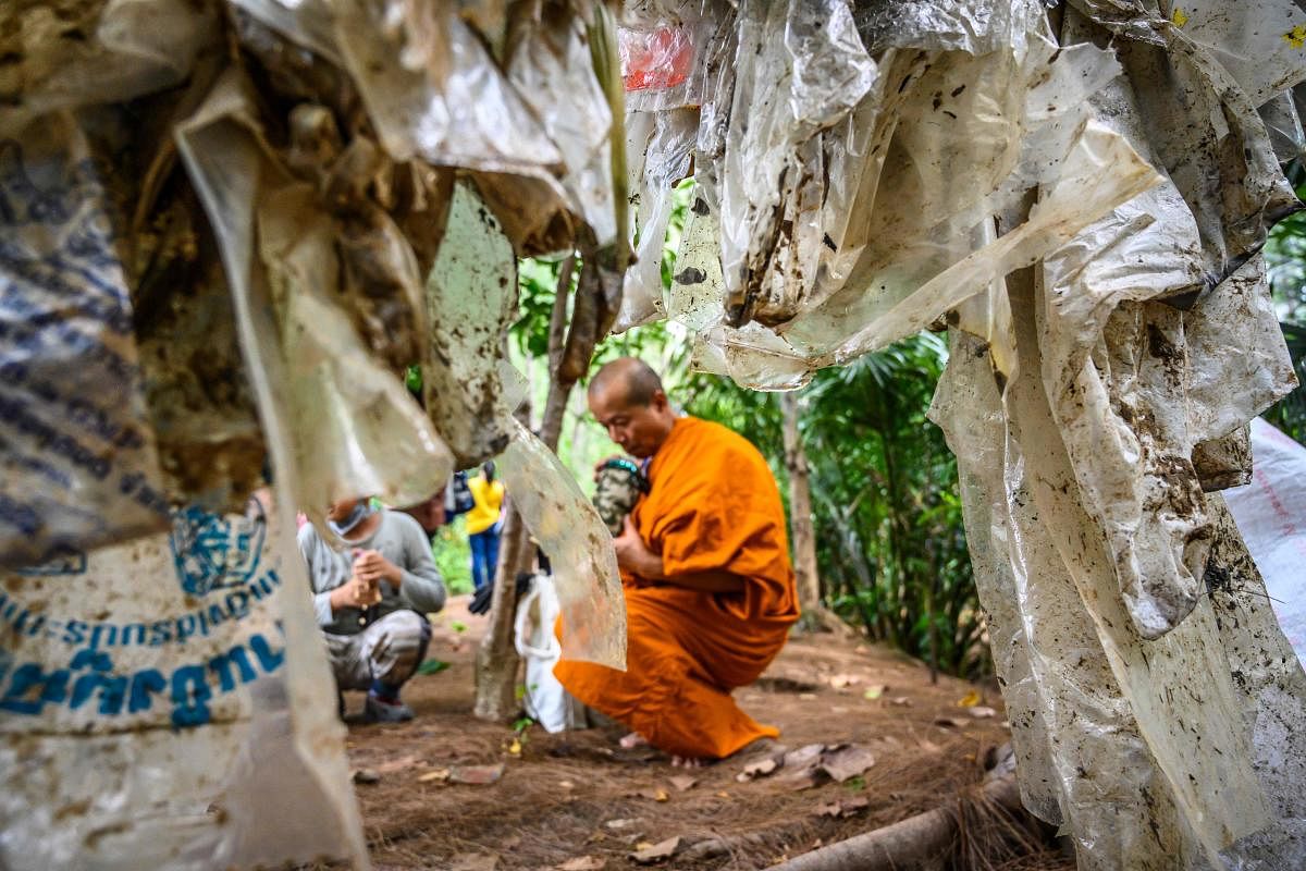A Buddhist monk sits next to used plastic bags at Khung Bang Kachao Urban Forest and beach collected as part of the Trash Hero initiative in Bangkok on August 25, 2019. (Photo by Mladen ANTONOV / AFP)