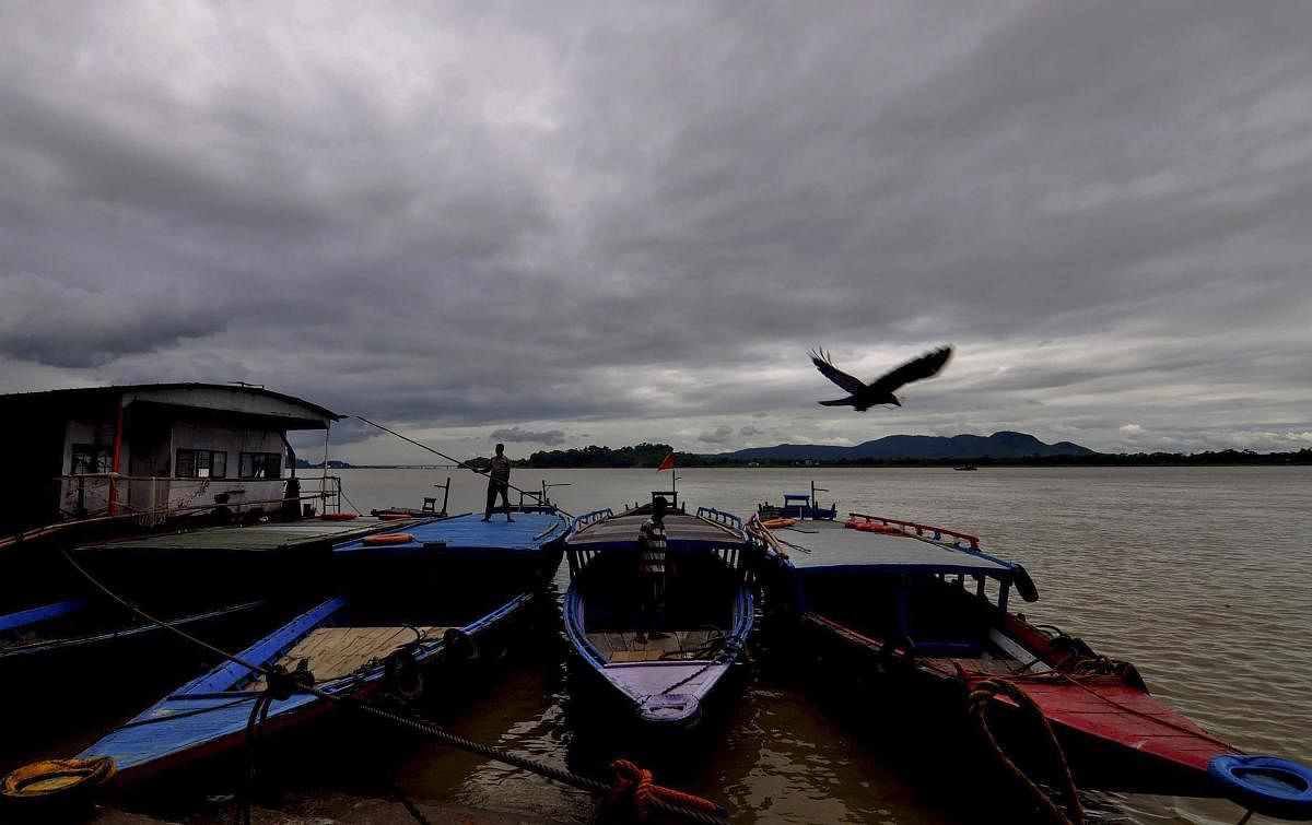 Monsoon clouds hover in the sky over Brahmaputra River as boats are anchored at its bank, in Guwahati on Tuesday. PTI Photo