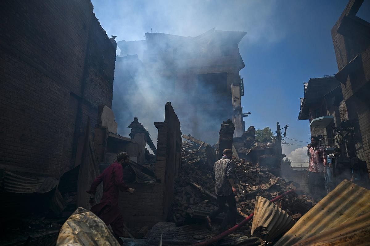 Residents gather around the debris of a house damaged in a gun battle between suspected militants and government forces in Srinagar on May 19, 2020. Credit: AFP Photo