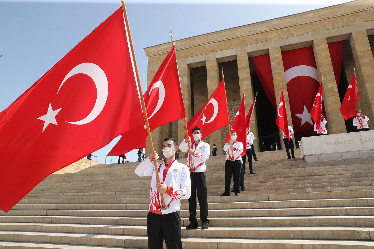 Turkish students wearing face masks for protection against the new coronavirus (COVID-19), wave national flags during a ceremony at the mausoleum of Mustafa Kemal Ataturk, in Ankara, on May 19, 2020. Credit: AFP Photo