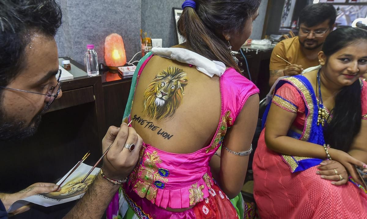 A woman gets her back painted on a theme to create awareness for 'Save the Lion', ahead of Navratri festival in Ahmedabad on Friday. PTI Photo