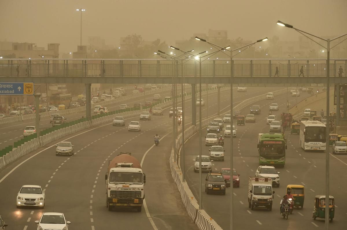 Vehicles ply slowly on a road as the weather turns hazy, in New Delhi on Tuesday. PTI Photo