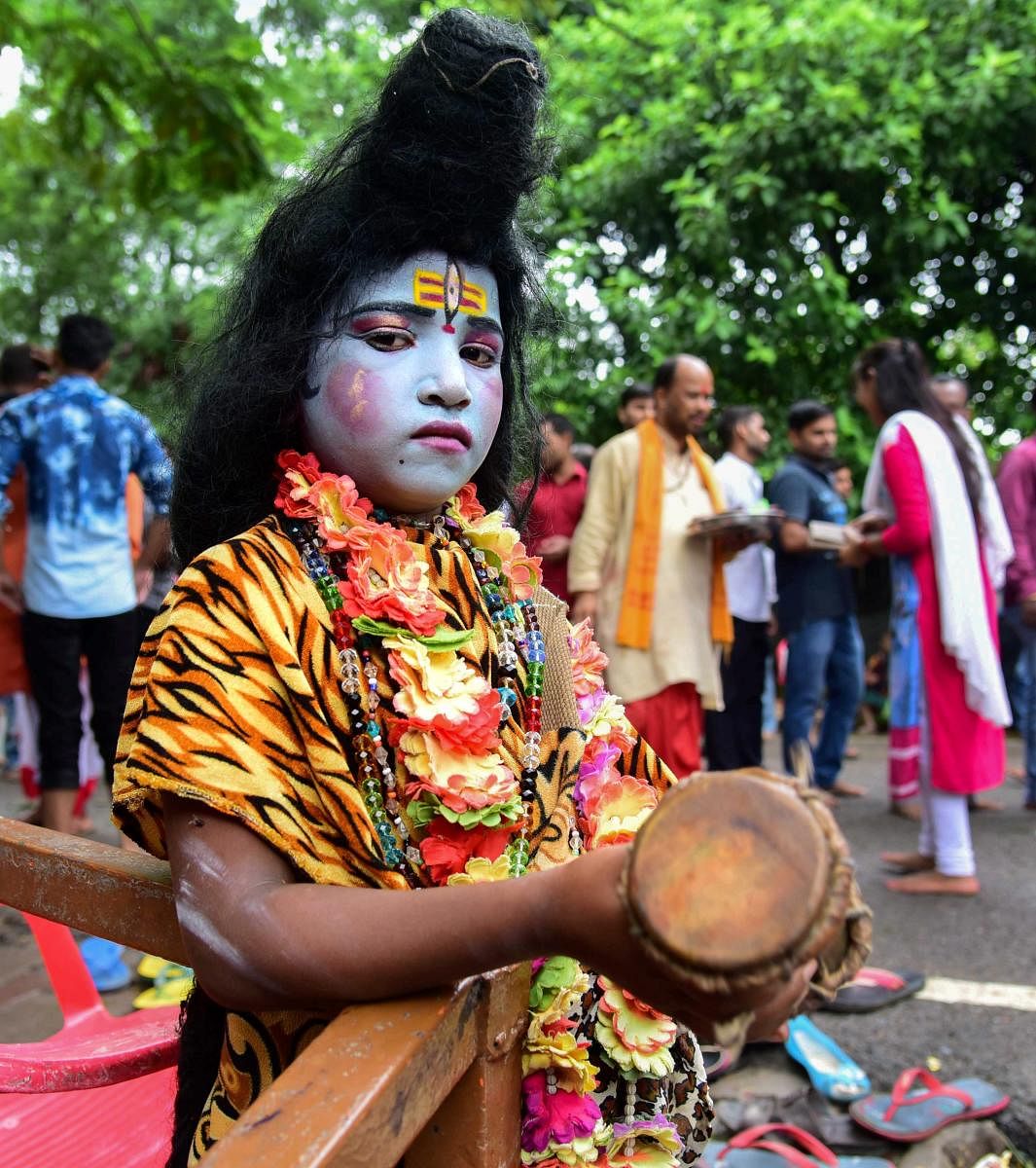 Allahabad: A child dressed as Hindu deity Shiva pose for a photographer outside a temple on the first Monday of the holy month of 'Shravan' at, in Allahabad on July 30, 2018. (PTI Photo)