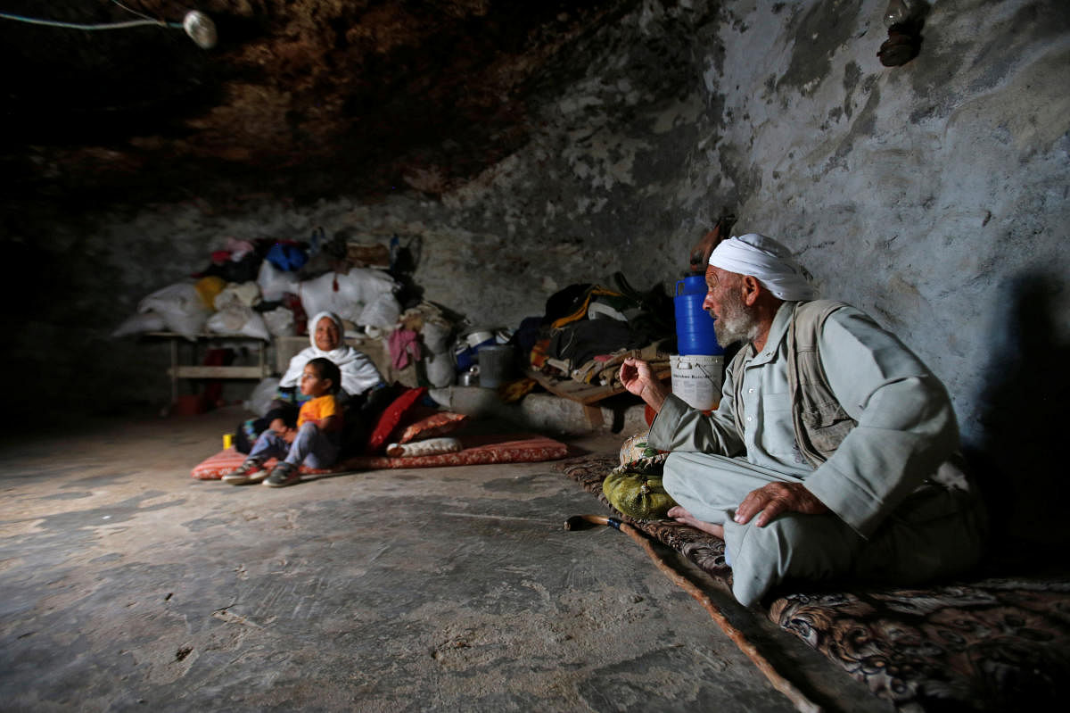 Members of a Palestinian family sit in a cave they live in, near Yatta in the Israeli-occupied West Bank. (REUTERS/Mussa Qawasma)
