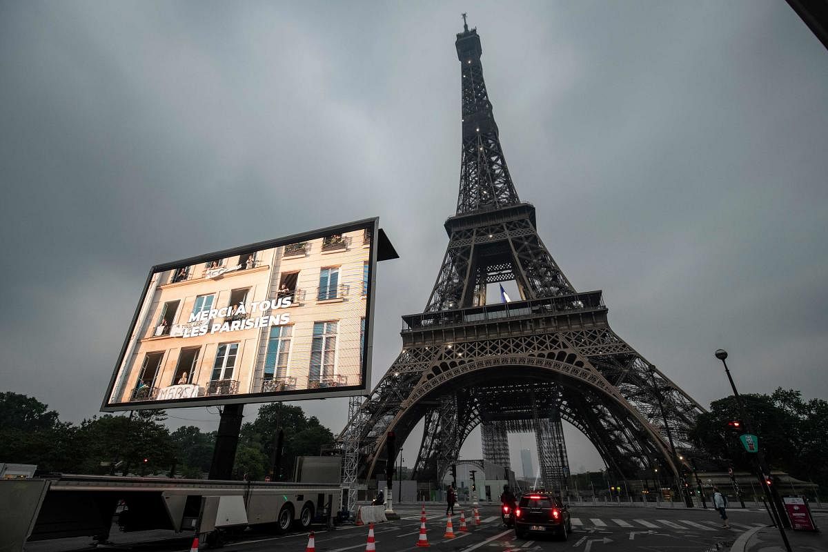The lettering 'Thank you to all Parisians' is displayed on a large digital screen following a tribute to representatives of professional groups who were mobilized during the COVID-19 pandemic, in front of The Eiffel Tower in Paris. Credit: AFP Photo