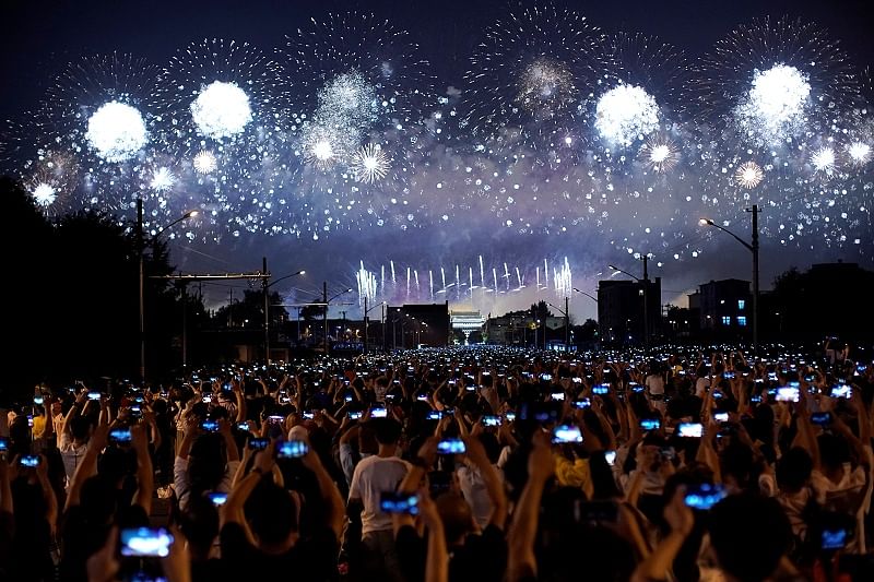 People on the street hold their phones as fireworks explode in the sky during an evening gala marking the 70th anniversary of the founding of the People's Republic of China. (Reuters)