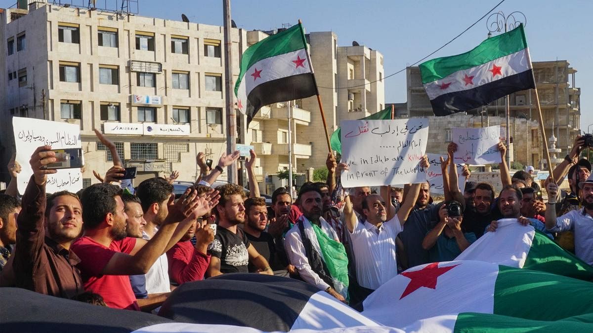 Syrians wave opposition flags as they demonstrate against Russia's interference in their town of Khan Sheikhun, in the rebel-held city of Idlib in northwestern Syria on August 27, 2019. (Photo by Muhammad HAJ KADOUR / AFP)