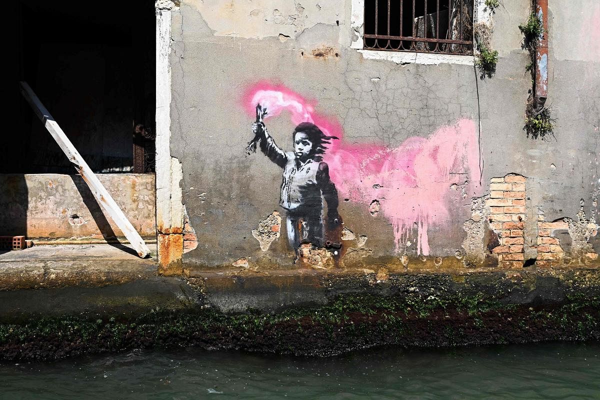 A mural by British street artist Banksy, of a child holding a pink flare, is pictured on August 27, 2019 on a building in Venice. (Photo by Vincenzo PINTO / AFP)