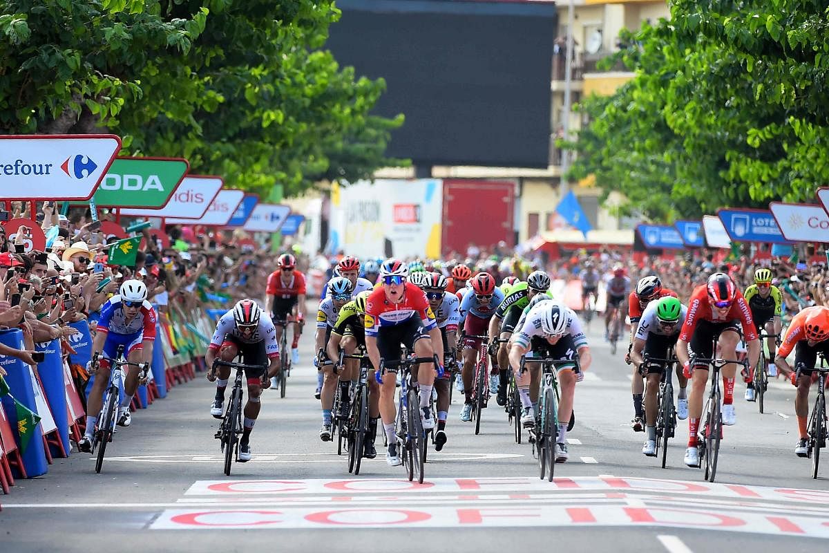 Team Deceuninck rider Netherlands' Fabio Jakobsen (C), Team Bora rider Ireland's Sam Bennett (4R) and Team Sunweb rider Germany's Max Walscheid (2R) cross the finish line of the fourth stage of the 2019 La Vuelta cycling tour of Spain, a 175,5 km route from Cullera to El Puig, on August 27, 2019 in El Puig. (Photo by JOSE JORDAN / AFP)