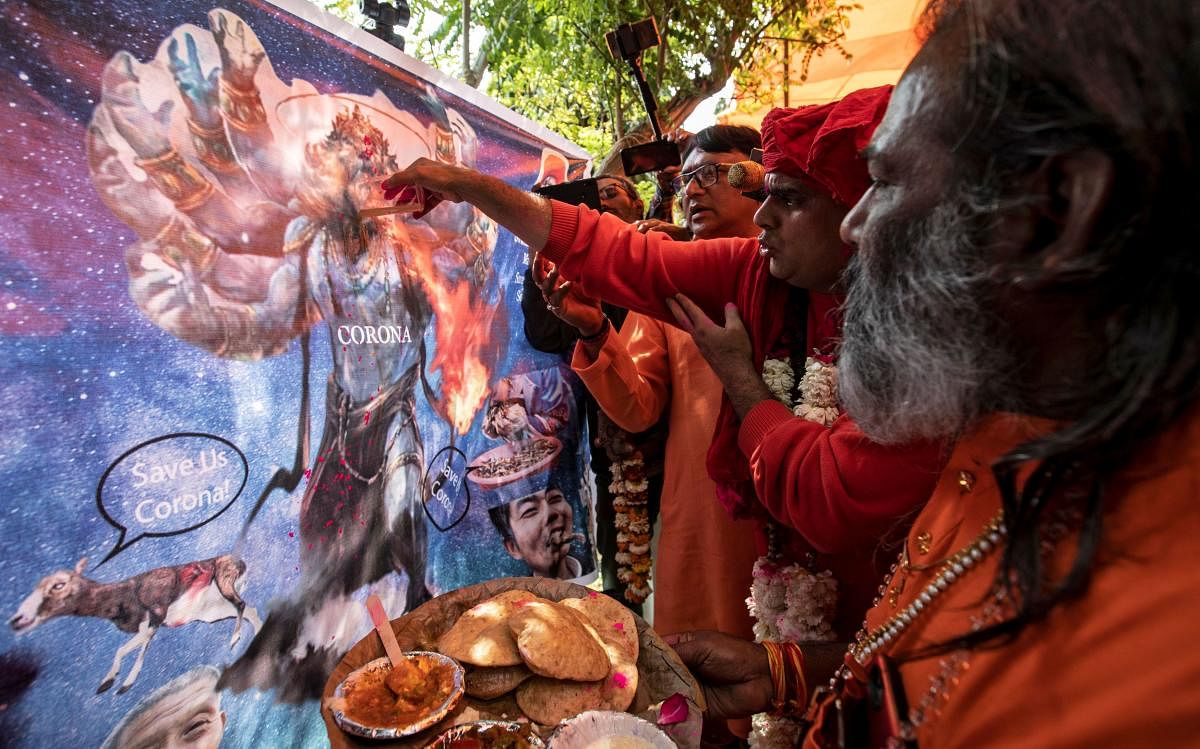 Members of All India Hindu Mahasabha offer cow urine to a caricature of the coronavirus as they attend a gaumutra (cow urine) party, which according to them helps in warding off coronavirus disease (COVID-19), in New Delhi, India March 14, 2020. (Reuters photo)