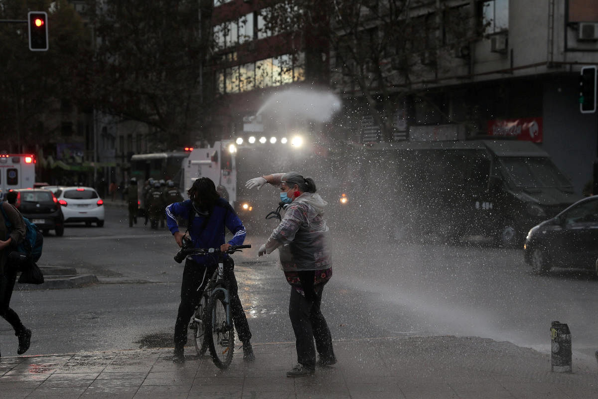 A riot police vehicle releases a jet of water during a protest against Chile's government despite social distancing recommended amid the coronavirus disease (COVID-19) outbreak, at Plaza Italia, now known as Plaza de la Dignidad (Dignity square), the main place of rallies since protests broke out in Chile over social injustices and entrenched inequality, in Santiago, Chile. (Reuters photo)