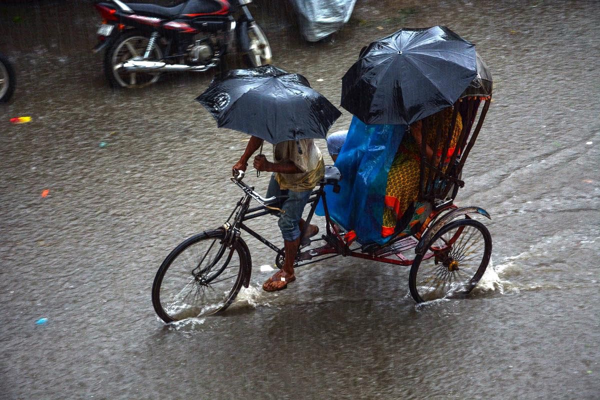 A rickshaw puller wades through a waterlogged street after heavy rainfall, in Agartala on Tuesday. PTI Photo