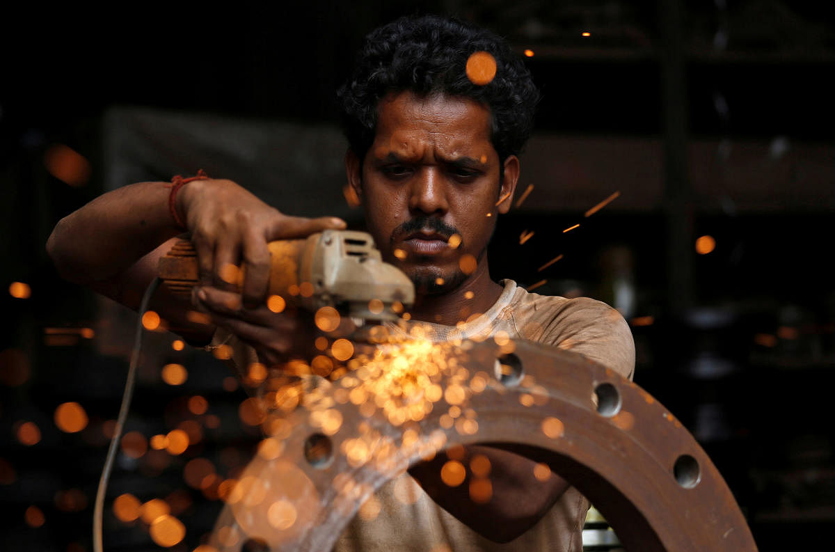 A man uses a disc grinder as he smoothens a flange ring at a workshop in an industrial area in Mumbai, India, August 2, 2018. REUTERS/Francis Mascarenhas