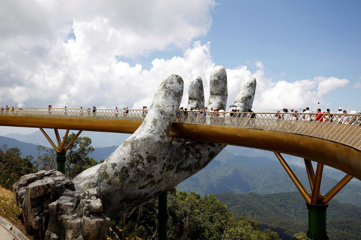 Tourists walk past giant hand structure on the Gold Bridge on Ba Na hill near Danang City, Vietnam August 1, 2018. REUTERS/Kham