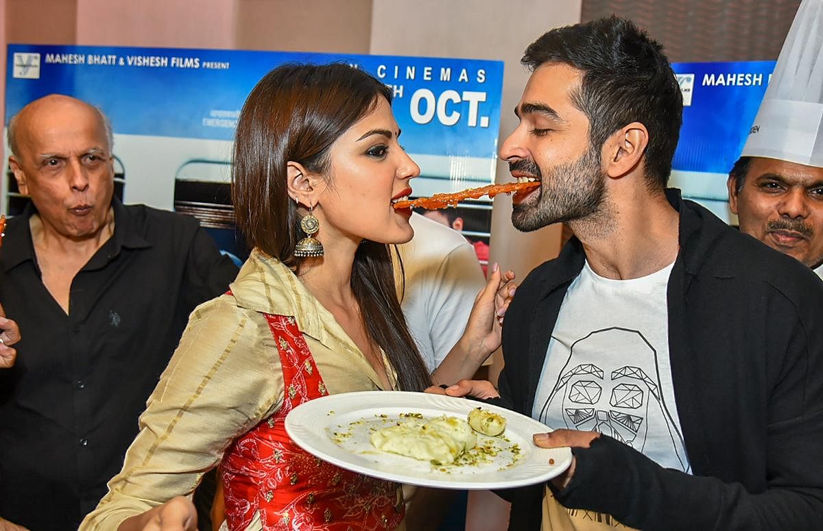 Bollywood actors Rhea Chakraborty and Varun Mitra share a 'jalebi' during a promotional event for their upcoming movie 'Jalebi', in New Delhi. (PTI photo)