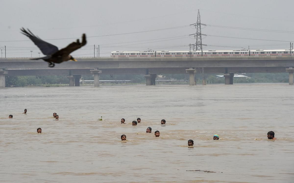 New Delhi: People swim across the swollen Yamuna river, in New Delhi on Sunday, July 29, 2018. (PTI Photo/Manvender Vashist)