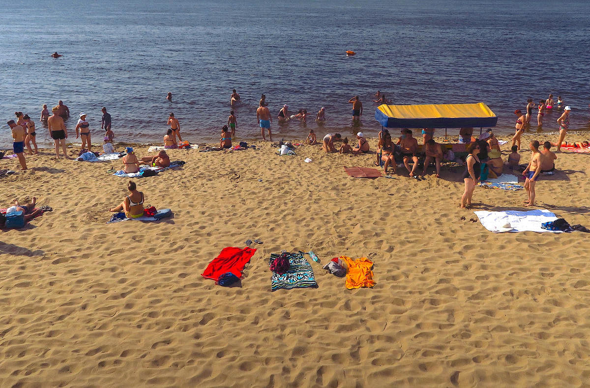 People sit on a beach as others swim in the Volga River in Samara, Russia. (Reuters Photo)
