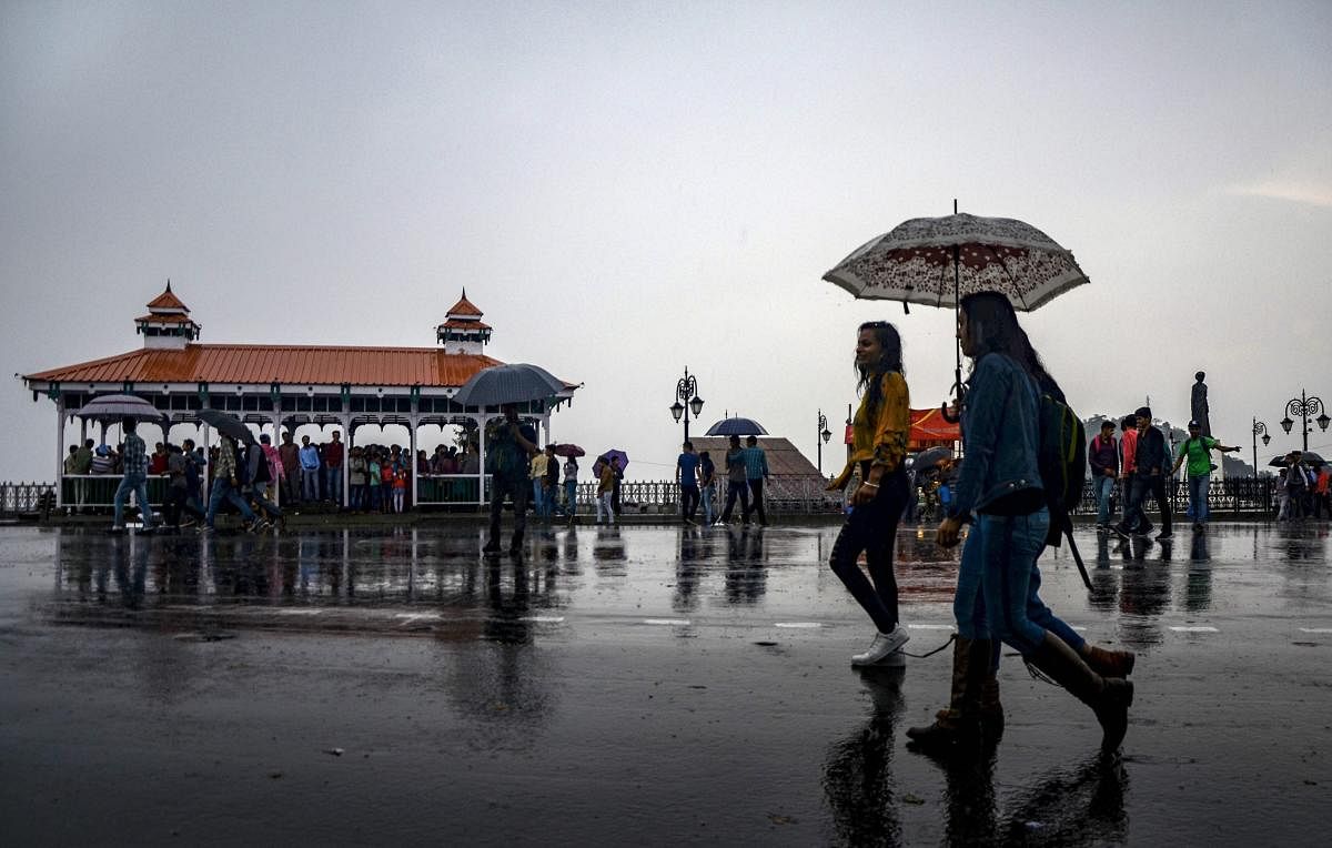 People walk with umbrellas during rain, in Shimla on Friday. PTI Photo