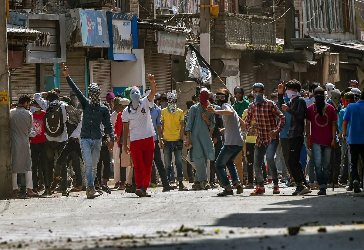Protesters throw stones at the security personnel during a protest, at Nowhatta, in Srinagar on Friday.  PTI Photo