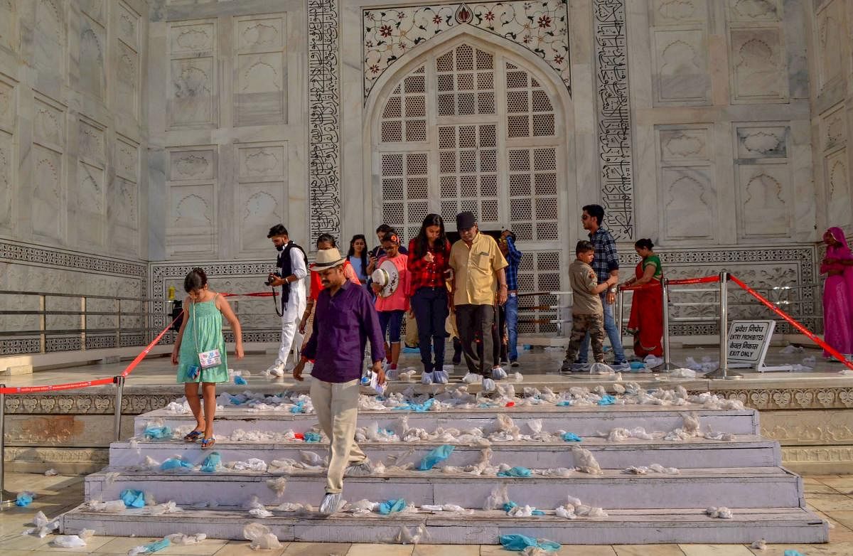 Tourists visit the Taj Mahal, as shoe-covers are seen lying on the steps, during a hot day, in Agra on Saturday. PTI Photo