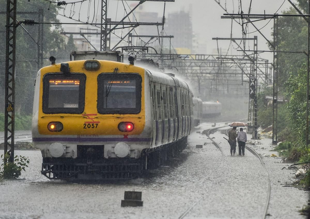 A local train chugs at waterlogged tracks following heavy monsoon showers in Mumbai on Saturday. PTI Photo