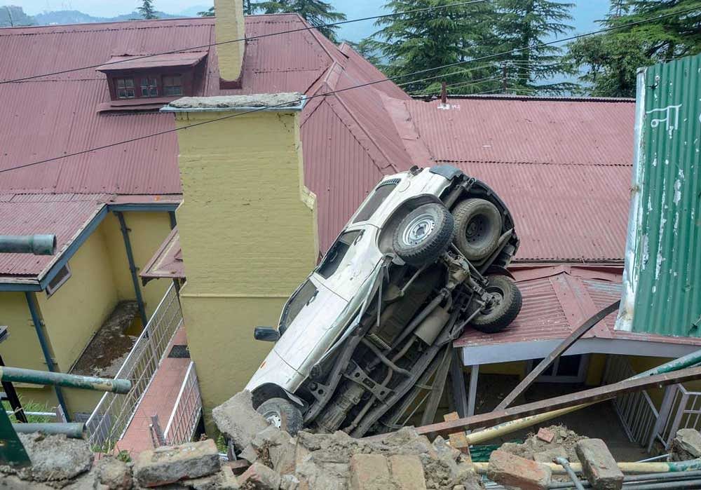 Mayor Kusum Sadret’s official vehicle on a house after it skidded off a road, in Shimla on Sunday, June 03, 2018. The accident took place after Saturday midnight. PTI Photo