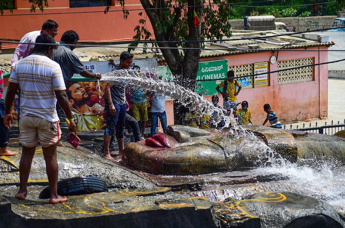 Devotees pour water over the 300-tonne monolithic stone statue of Vishwaroopa Mahavishnu which is to be installed in the premises of the Kothandaramaswamy Temple, in Bengaluru. PTI Photo