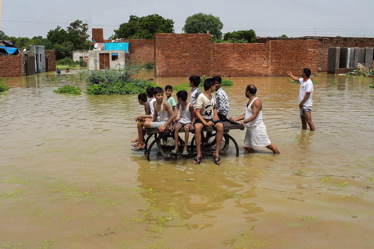 Mathura: Children ride a cart as they move through a flooded colony, inundadted by the Yamuna river, in Mathura on Thursday, Aug 2, 2018. (PTI Photo)