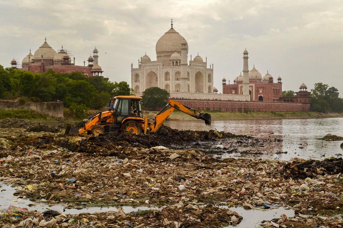 An earthmover removes debris from the Yamuna river bed against the background of Taj Mahal, in Agra, Sunday, June 16, 2019. PTI