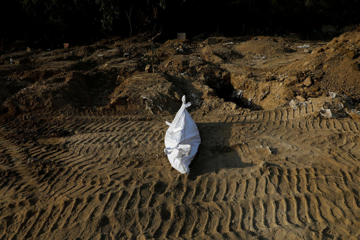 The body of a Muslim man who died from the coronavirus disease (COVID-19) is seen near the grave before the burial at a graveyard in New Delhi, India. Credit: Reuters Photo