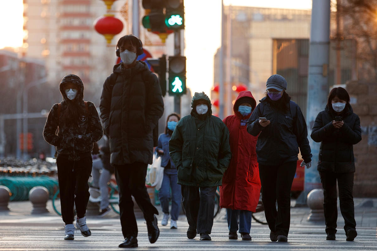 People wear masks as they cross a street during evening rush hour, as the country is hit by an outbreak of the novel coronavirus, in Beijing. Credit: Reuters Photo