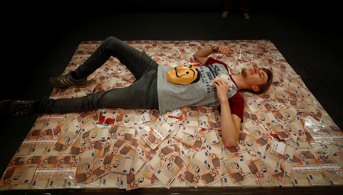 A man gets his picture taken from a roof camera as he lies on a bed of money of the Netflix series Money Heist during the media day of Europe's leading digital games fair Gamescom. (Photo: Reuters)