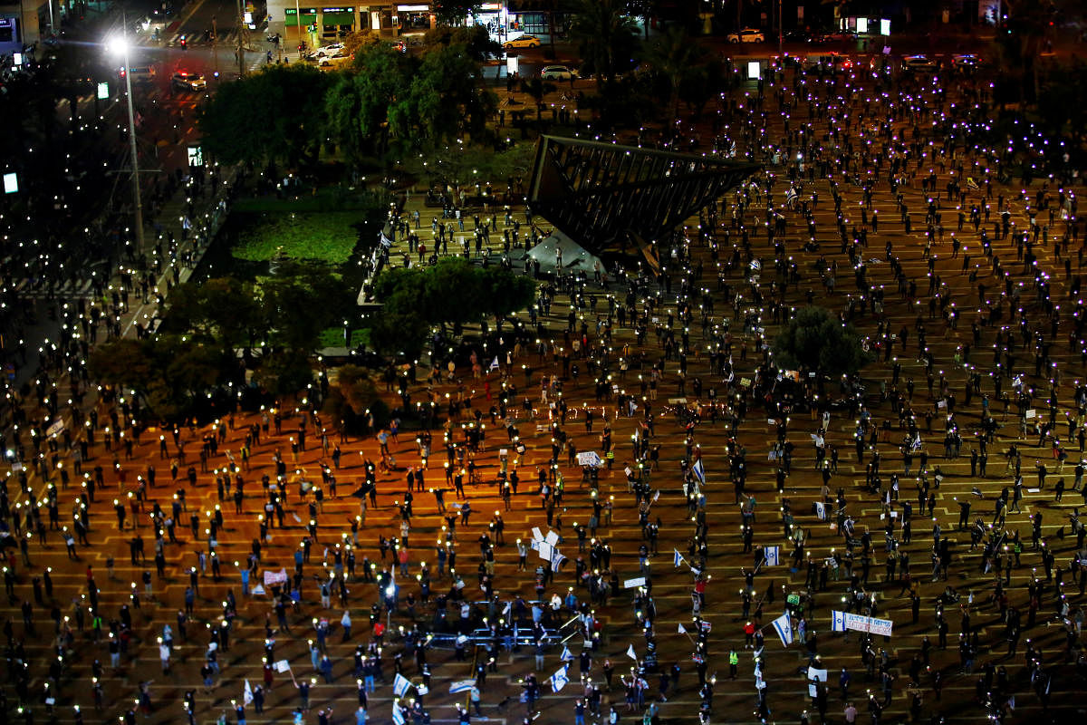 Israelis hold up their mobile phones as they demonstrate against Israel's Prime Minister Benjamin Netanyahu, under strict restrictions made to slow down the coronavirus disease (COVID-19) spread, on Rabin Square in Tel Aviv, Israel April 19, 2020. Credit: Reuters Photo