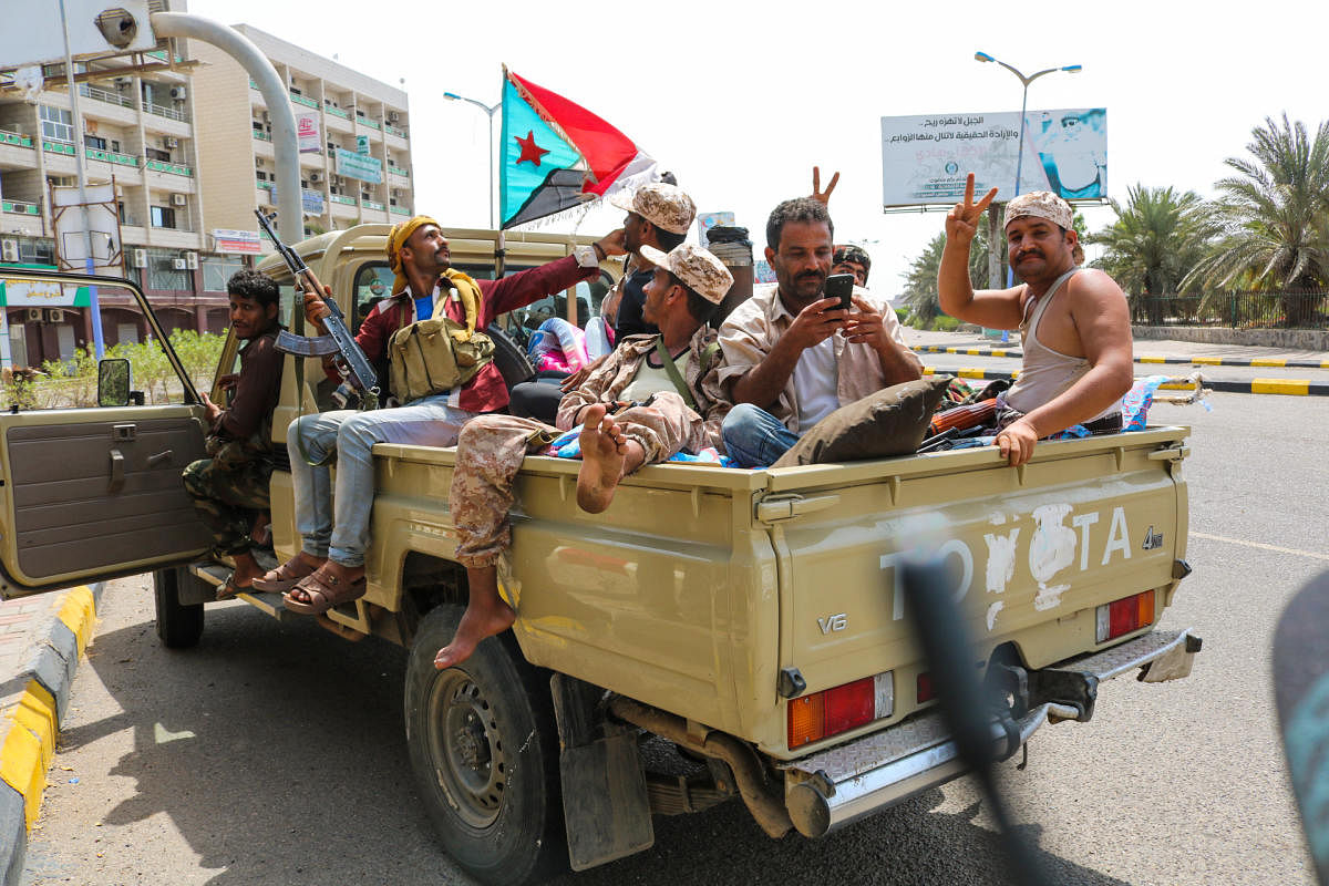 Fighters of the UAE-trained Security Belt Force, dominated by members of the Southern Transitional Council (STC) which seeks independence for south Yemen, flash the victory gesture as they sit with a southern separatist flag (the old flag of South Yemen) in the back of a pickup truck near the Aden Hotel in the Khor Maksar district of the second city of Aden on August 29, 2019. (Photo by Nabil HASAN / AFP)