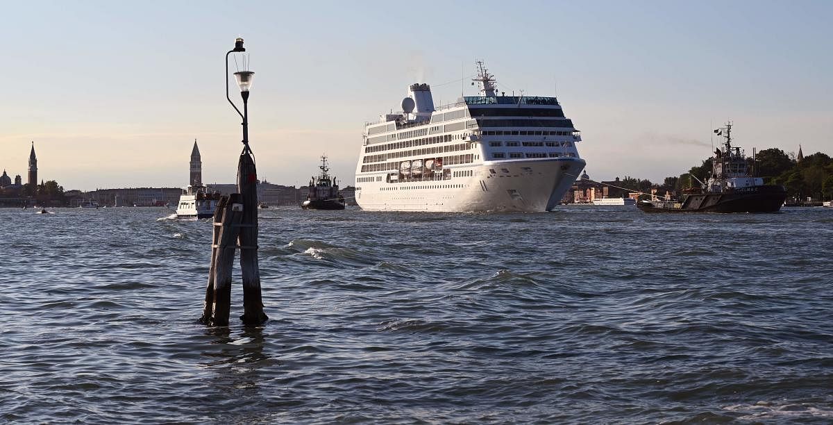 The Oceania Cruises 'Sirena' cruise ship is pulled by three tugboats upon its arrival in the Venice Lagoon in Venice on September 3, 2019, as the St Mark's Bell Tower (L) is seen in the background. (Photo by Alberto PIZZOLI / AFP)