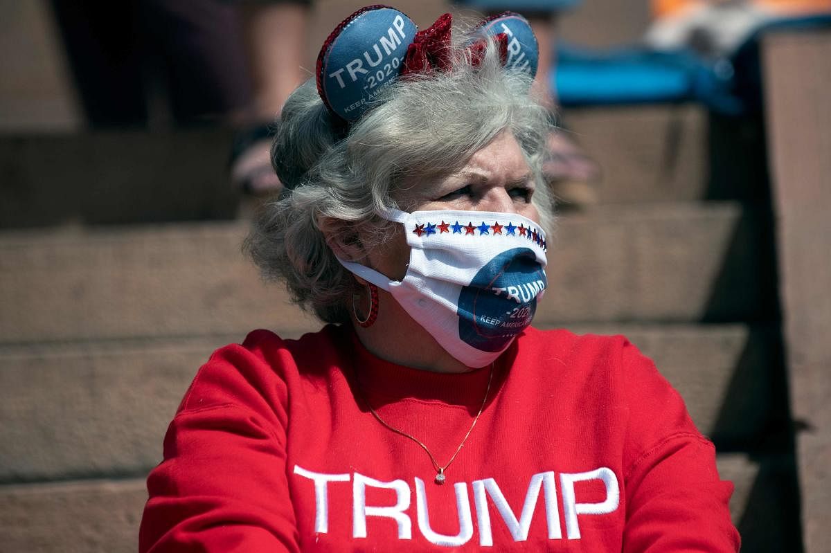 A demonstrator wearing a Trump 2020 face mask gathers with others to protest coronavirus stay-at-home orders during a